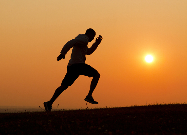 Sunset silhouette of a man running uphill